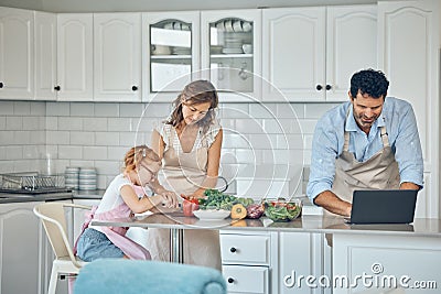 Kitchen, cooking and family with laptop with vegetables, food nutrition information and internet recipe search for Stock Photo