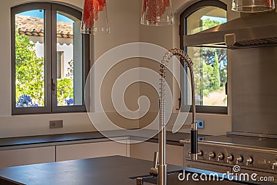 Kitchen corner with a large stainless steel faucet, a steel gas stove, and white furniture Editorial Stock Photo