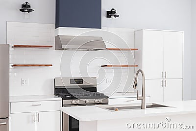 A kitchen detail with white cabinets, tiled backsplash, and blue oven hood. Stock Photo