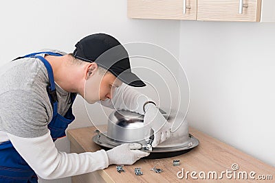 Kitchen furniture assembly worker inserts fixtures into the sink to secure it Stock Photo