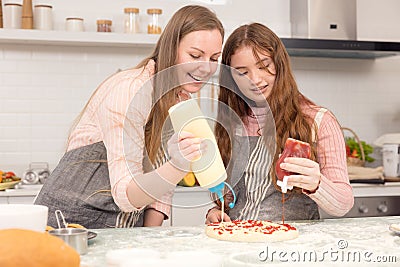 In the kitchen at home, a playful mother and daughter yell while making pizza dough Stock Photo