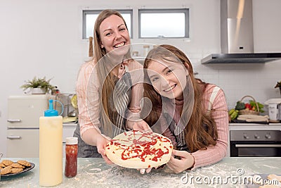 In the kitchen at home, a playful mother and daughter yell while making pizza dough Stock Photo