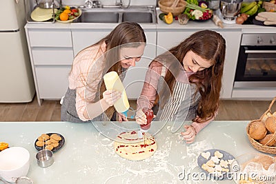 In the kitchen at home, a playful mother and daughter yell while making pizza dough Stock Photo