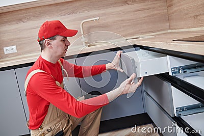 Kitchen installation. Worker assembling furniture Stock Photo