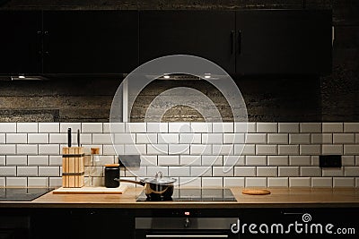 Kitchen interier. black cabinets, white tiles. the pan is on the stove. Scandinavian style kitchen Stock Photo