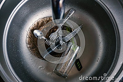 Kitchen sink with dirty pots, flowing tap Stock Photo