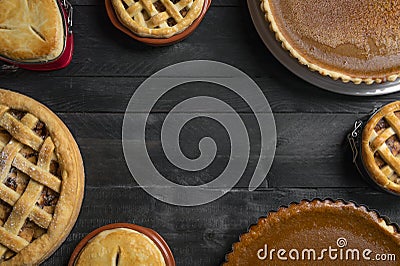 Kitchen table full of different pies, pumpkin pies, apple pies, with empty space in the middle. Traditional holidays dessert. Stock Photo