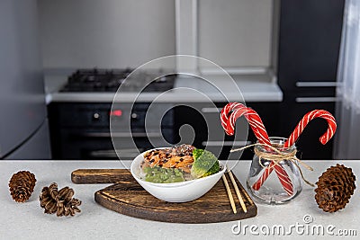 On the kitchen table is a plate of golden rice, king prawns, green beans and broccoli Stock Photo