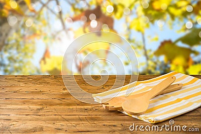 Kitchen utensils and tablecloth on wooden table over autumn bokeh background Stock Photo