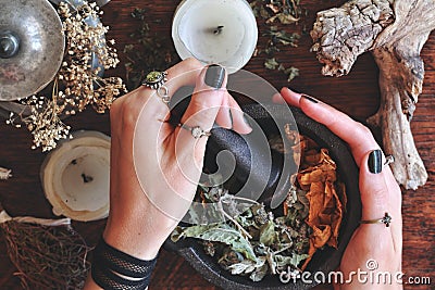 Kitchen witchery - female wiccan witch holding pestle and mortar in her hands, making magickal herb blend for a spell Stock Photo