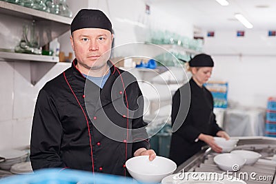 Kitchen worker arranging cleaned dishes Stock Photo