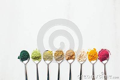 Kitchenware with different colorful superfood powders on wooden table Stock Photo