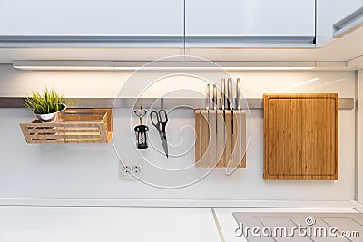 Kitchenware hanging on the rail in the white glossy kitchen Stock Photo