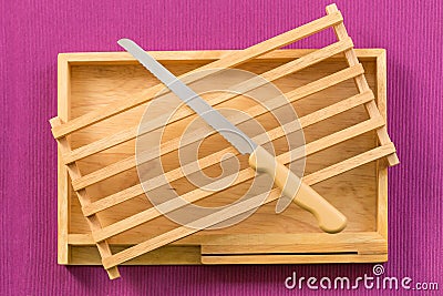 Kitchenware, Vintage cutting bread wood block and tray with stainless steel knife on purple tablecloth Stock Photo