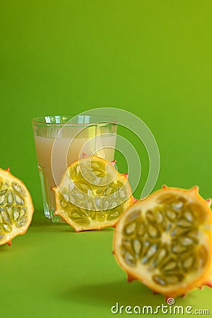 Kiwano slice, exotic vegetable cucumis metuliferus and a glass of fruit juice on a green background. Soft focus. Vegetarian food Stock Photo