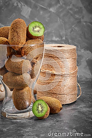 Kiwi fruits half sliced in glass bowl on dark black moody plain background, angle view Stock Photo