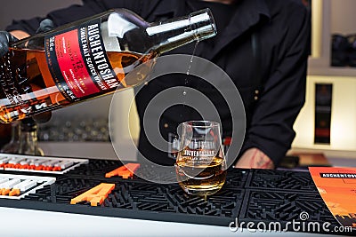 Kiyv, Ukraine, November 22, 2020. Bartender pours 12-years single malt Auchentoshan Scotch Whiskey into a glass at the bar. Pourin Editorial Stock Photo