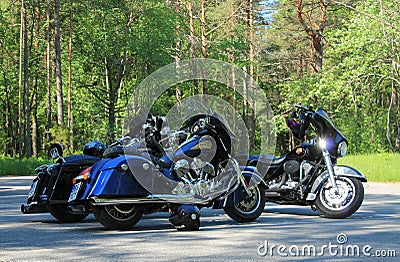 Three black motorcycles in a parking lot in the forest Editorial Stock Photo