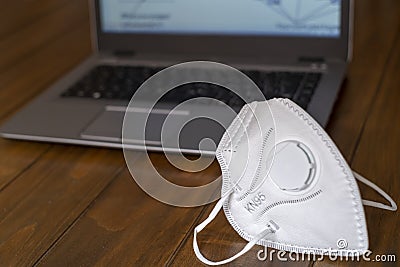 KN95 FPP2 Corona Virus Protection face mask on a wooden desk with a laptop computer out of focus Stock Photo