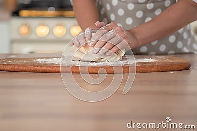 Knead dough, hand dough and flour close-up. A pastry chef in a grey polka-dot apron. Stock Photo