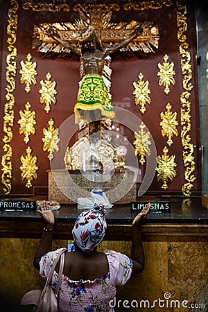 Kneeling woman praying in front of the sacred image of the Lord of Miracles at Minor Basilica of the Lord of Miracles located in Editorial Stock Photo