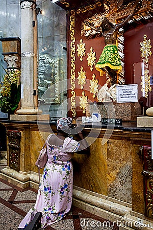 Kneeling woman praying in front of the sacred image of the Lord of Miracles at Minor Basilica of the Lord of Miracles located in Editorial Stock Photo