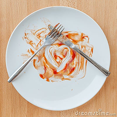 Knife and fork crossed in finish plate and heart shape ketchup, Stock Photo