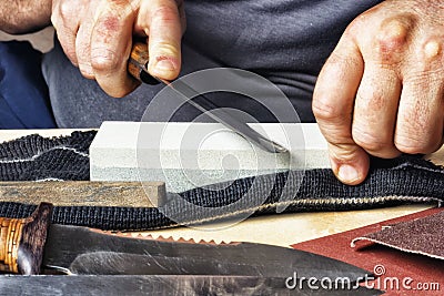 Knife in hand sharpening on a whetstone. Stock Photo