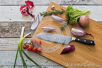 Knife with healthy food - vegetables, onion, salad, tomatoes, potato placed on a cutting board with wood background top view Stock Photo