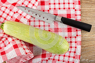 Knife, squash marrow on napkin on wooden table. Top view Stock Photo