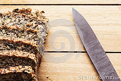 Knife and wholemeal, wholewheat bread on wooden table. Organic, healthy food Stock Photo