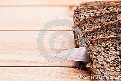 Knife in wholemeal, wholewheat bread on wooden table. Organic, healthy food Stock Photo