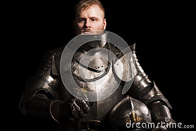 Knight in armour after battle on the black background Stock Photo