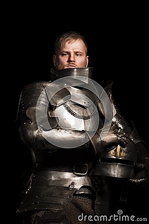 Knight in armour after battle on the black background Stock Photo