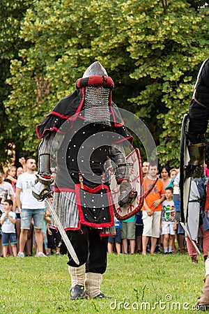 Brave Knight in Red Armor Wields Sword and Shield: Thrilling Battle Reconstruction at the International Knights Festival Editorial Stock Photo