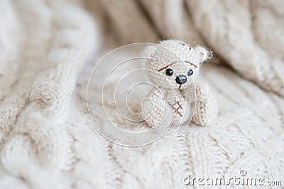 Knitted beige bear sits on a plaid of handmade Stock Photo