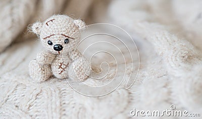 Knitted beige bear sits on a plaid of handmade Stock Photo