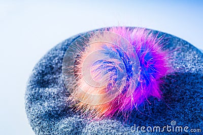 Knitted beret with a bright colorful artificial fur pompom Stock Photo