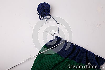 Knitted clothing, accessory in process of making. Knitting needles and ball of threads, yarn on white background. Striped blue, Stock Photo
