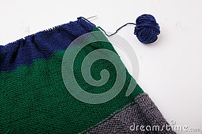 Knitted clothing, accessory in process of making. Knitting needles and ball of threads, yarn on white background. Striped blue, Stock Photo