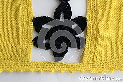 Knitted handmade fabric. The edge of the product is crocheted. The flower is sewn to the edge with a thread. Stock Photo