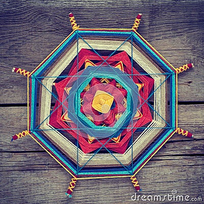 Knitted tibetan mandala from threads on wooden background Stock Photo