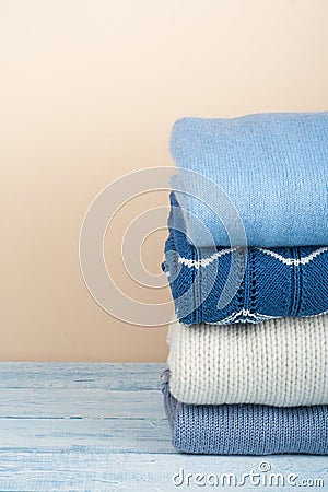 Knitted wool sweaters. Pile of winter clothes on yellow wooden background, , knitwear, space for text. Stock Photo