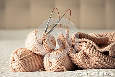 Knitting yarn, needles, chunky sweater. Cozy homely atmosphere. Yarn in warm colors of peach, beige. Knitting as a hobby. Stock Photo