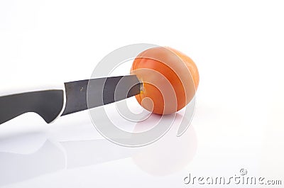 A knive cutting a tomato on white background Stock Photo