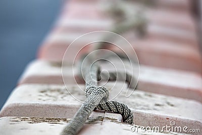 Knot on boat bollard detail on blue water background Stock Photo