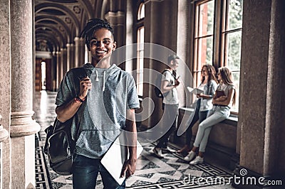 Knowledge empowers you.Handsome young student standing at the hall of campus and smiling Stock Photo