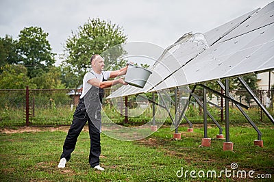 Knowledgeable worker cleaning solar PV batteries. Stock Photo