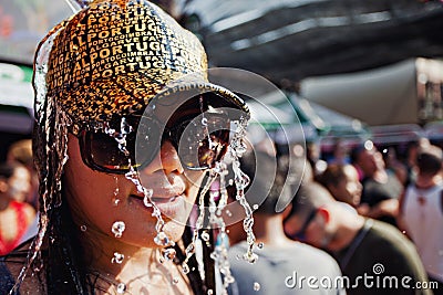 KO SAMUI, THAILAND - APRIL 13: Unidentified girl in a baseball cap under water jets in a water fight festival or Songkran Festival Editorial Stock Photo