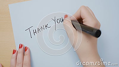 Kobiet ręki z czerwonym gwoździa połysku writing dziękują was na błękitnym papierze z czarnym markierem - zdjęcie wideo Kobiet ręki z czerwonym gwoździa połysku writing dziękują was na błękitnym papierze z czarnym markierem - zdjęcie wideo